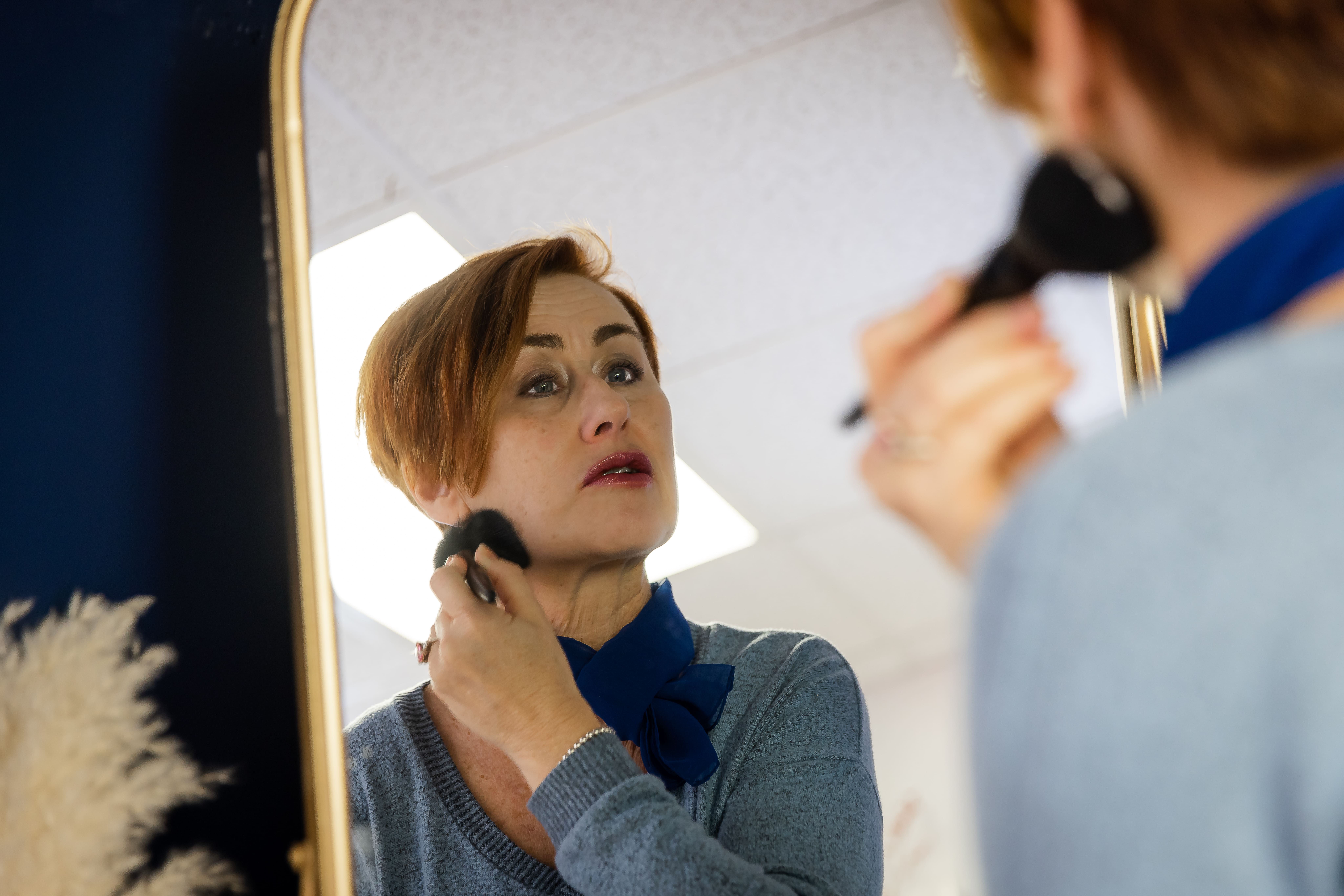 Woman standing confidently in front of mirror, representing clarity, confidence, and being seen in your brand.