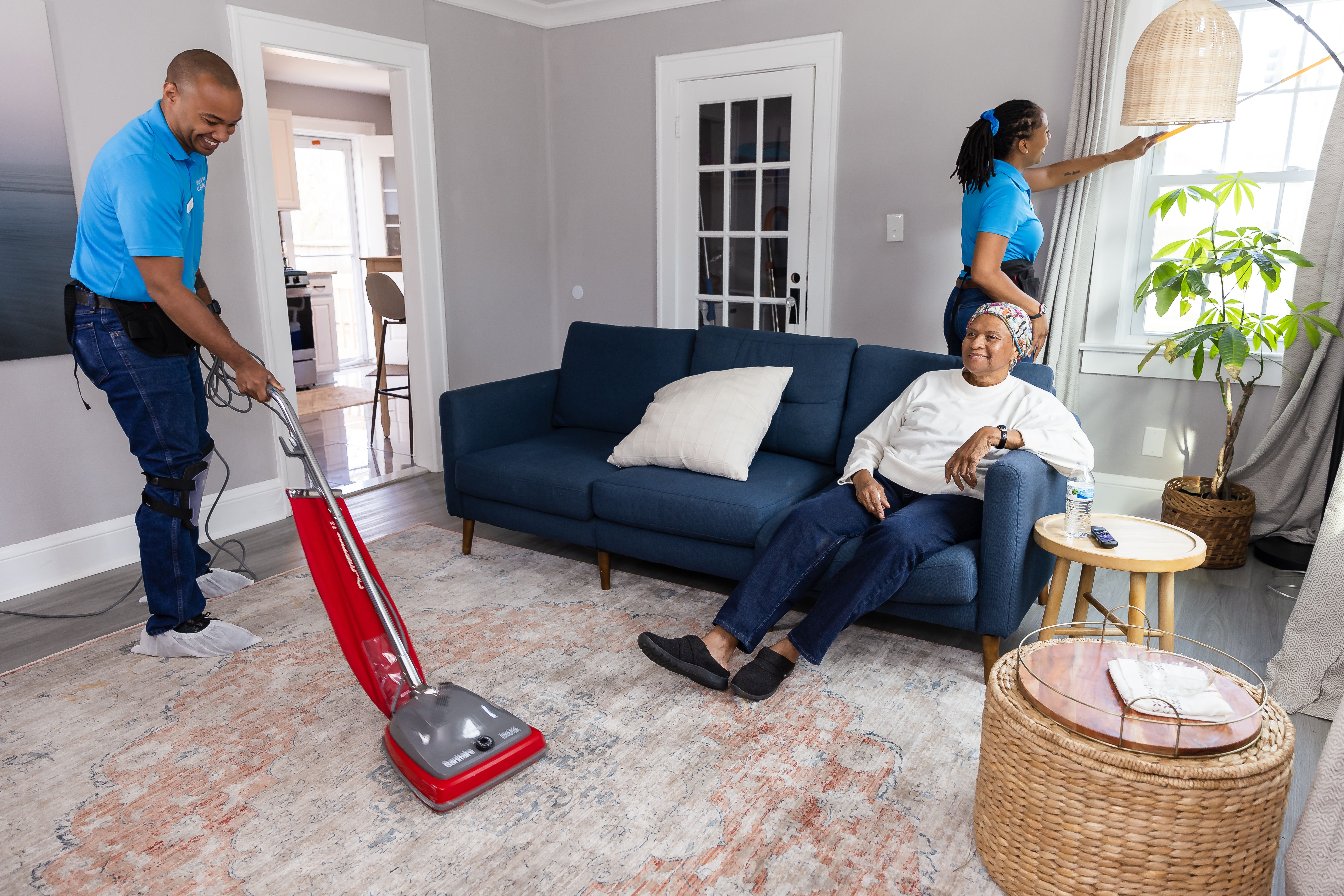 photo of older woman sitting on coach enjoying tv, while having her home professionally cleaned.